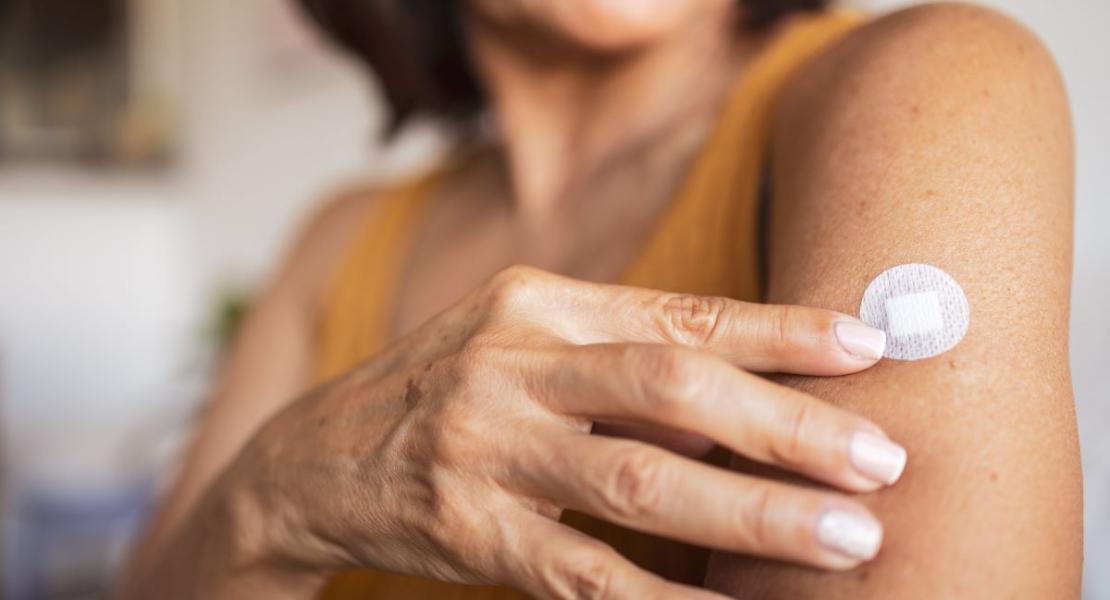 woman pointing to a hormone replacement therapy patch she has on her arm