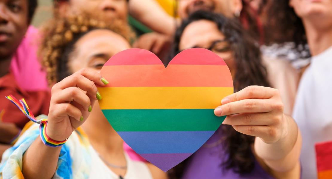 two people holding a rainbow painted heart