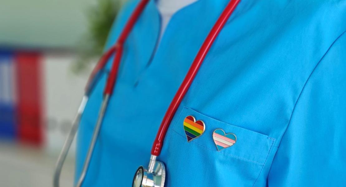 health care provider wearing a stethoscope and a heart shaped rainbow pin
