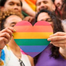 two people holding a rainbow painted heart