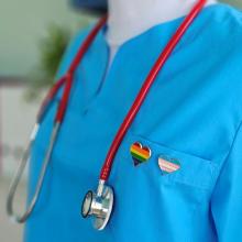 health care provider wearing a stethoscope and a heart shaped rainbow pin
