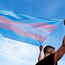 person holding a transgender pride flag over their head