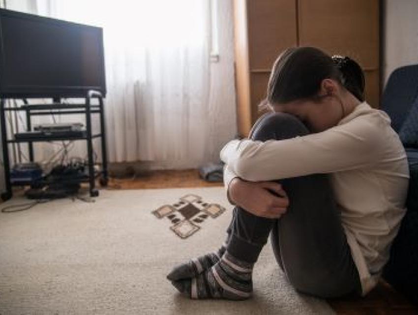 young girl sitting on the floor looking sad